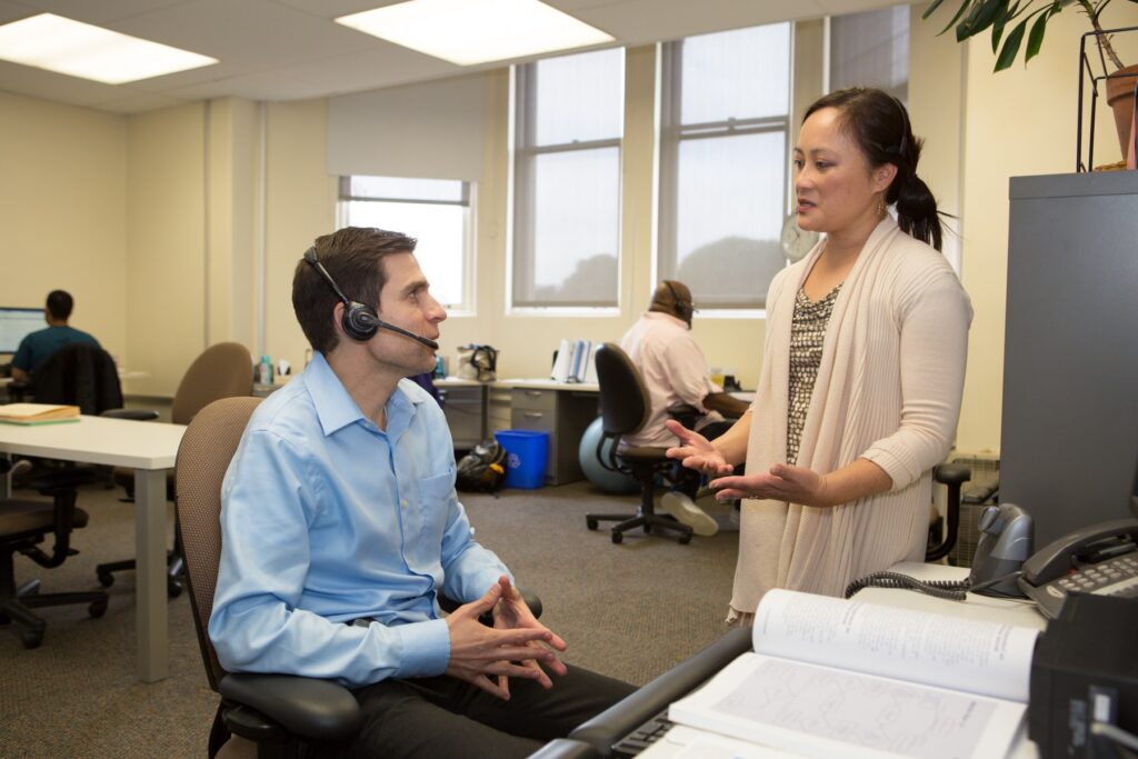 Dr. Gruta provides guidance to Jonathan Van Nuys, RN, MS, ANP-BC in the NCCC’s old call center, dubbed “clinician’s alley” (Photo for UCSF Magazine)